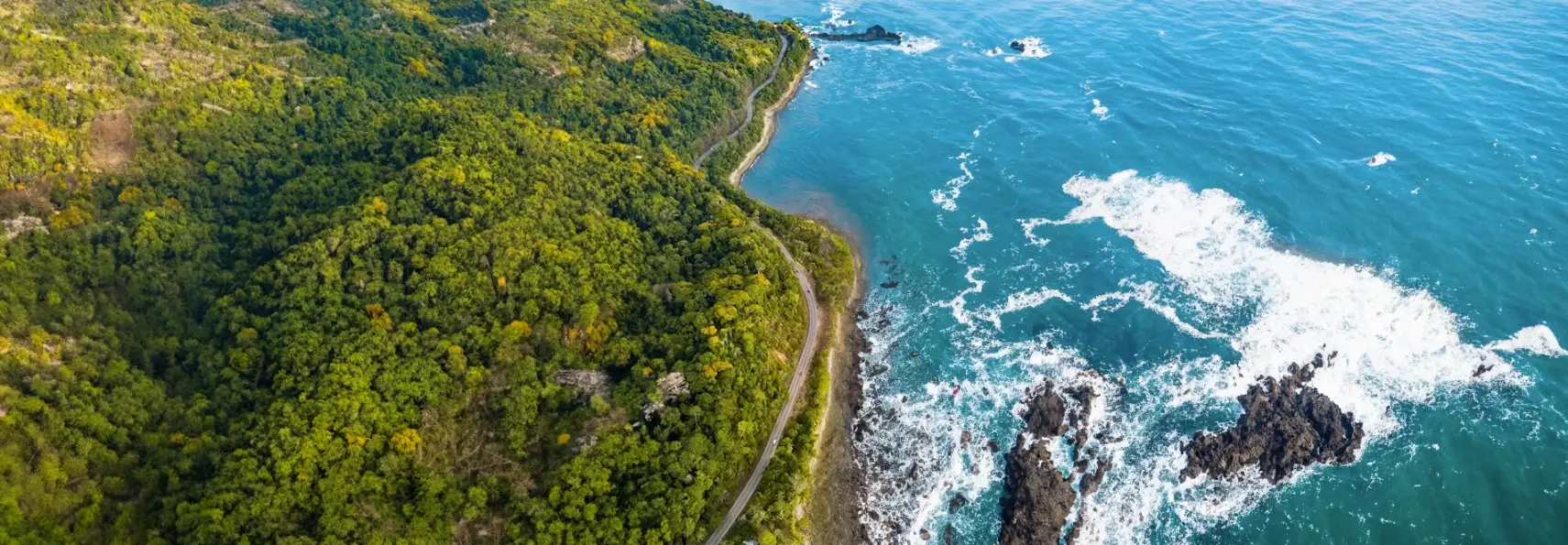 Vue aérienne d'une route côtière longeant l'océan Pacifique au Costa Rica, idéale pour un road trip en voiture de location