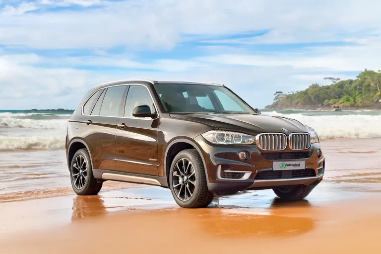 BMW X5 marron stationné sur une plage tropicale du Costa Rica, illustrant un SUV de luxe pour des vacances inoubliables