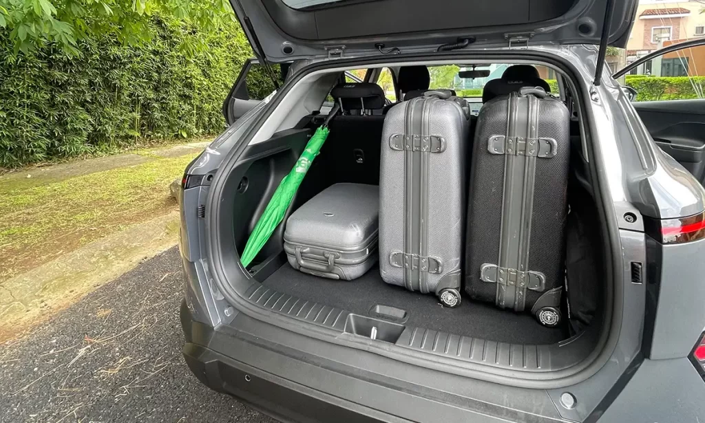 Coffre du Hyundai Kona 2WD avec trois valises et un parapluie vert, démontrant sa capacité pratique