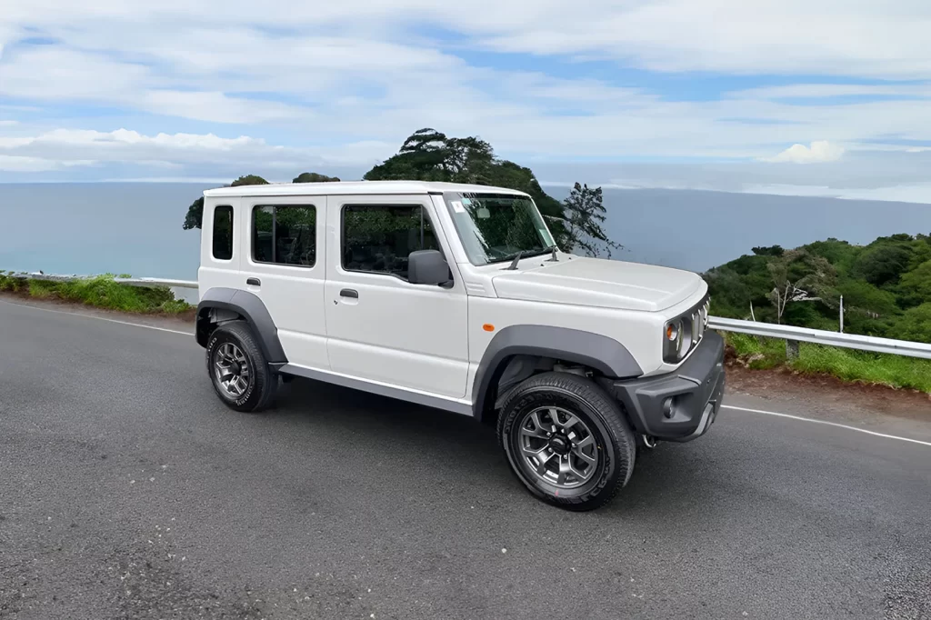Suzuki Jimny 4x4 blanc stationné sur une route panoramique au Costa Rica avec vue sur l’océan